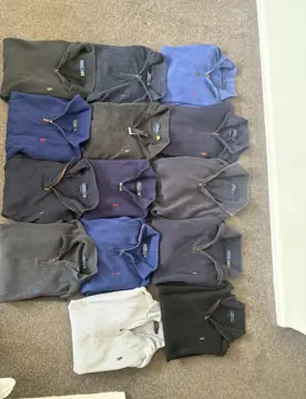 Nineteen Polo Ralph Lauren quarter zips laid out on carpet