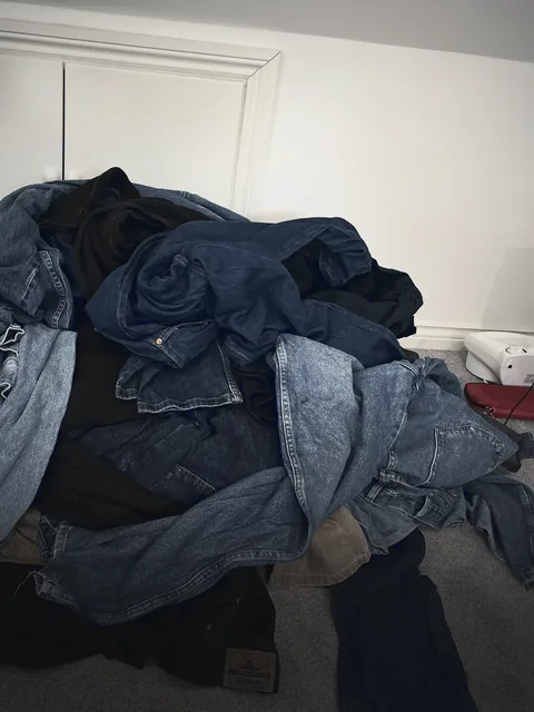 A wholesale bundle of jeans piled on a bedroom floor